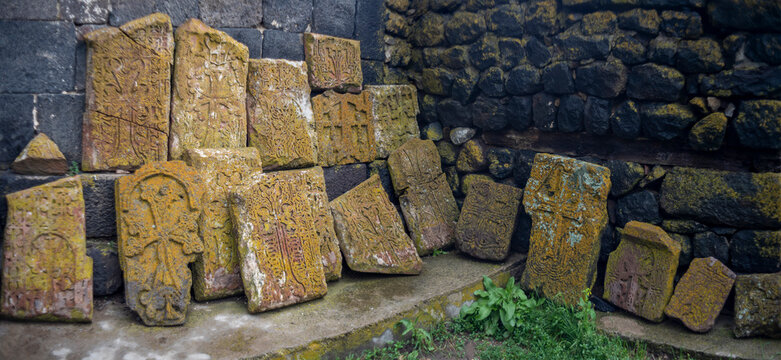 Ancient Armenian khachkars with carved stone crosses by monastery wall, historic background with copy space