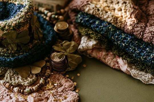 St. Patricks Day flat lay with a crocheted leprechaun hat, golden coins, and paper shamrocks on a green surface for festive holiday greetings