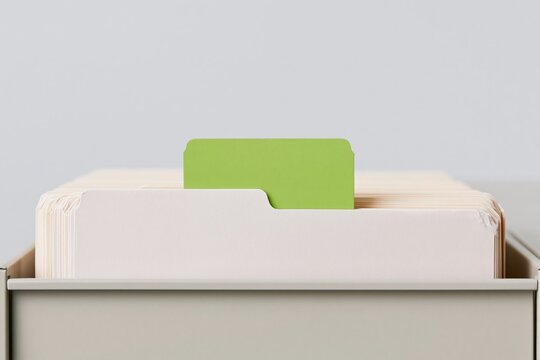 A single green file tab stands out among cream manila folders in an office drawer, featuring clean card stock textures and copy space for legal services