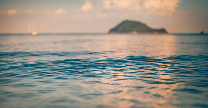 Tranquil sunset calm sea glassy water surface closeup blur island soft summer light. Peaceful artistic minimal ocean nature seascape. Meditation wellbeing background scenic landscape abstract design
