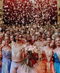 Obraz premium Diverse ballet dancers celebrate a theatrical curtain call as wooden snowflakes fall around a Black female lead for holiday arts marketing