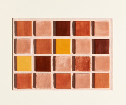 Regular grid of terracotta fabric and velvet swatches on linen for an interior design mood board, featuring warm ochre and espresso wood samples