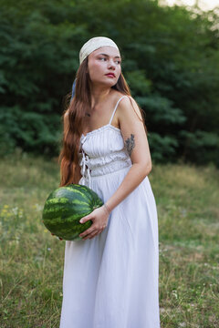 Cottagecore style female model holding big watermelon in forest