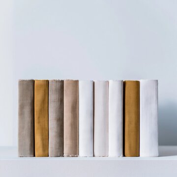Row of vintage cloth bound book spines with weathered fabric covers in muted sage and slate for interior design and library background