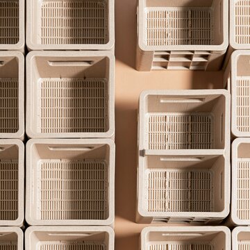 Mocha brown reusable stacking crates in a symmetrical aerial arrangement for warehouse logistics and supply chain management concepts