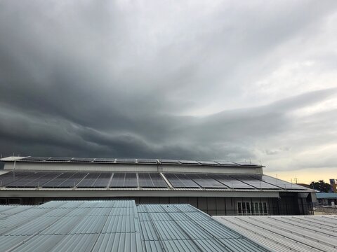 Solar Panels Under a Stormy Sky: A building's rooftop is covered with solar panels, set against a dramatic sky filled with dark, swirling storm clouds.