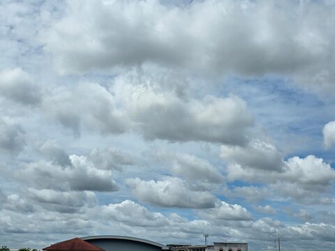 Sky with Cumulus Clouds: A bright sky filled with fluffy cumulus clouds over a small town landscape, suggesting a beautiful summer day.
