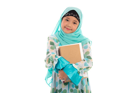 Adorable Muslim girl in mint green hijab holding books smiling at camera isolated in white studio.