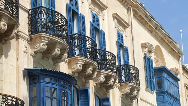 row of wrought iron balconies with teal shutters lines a baroque valletta palazzo facade carved stone corbels maltese balcony gallarija wooden balcony valletta architecture traditional maltese window