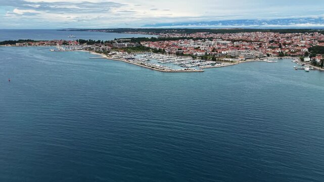 Wide aerial view of Zadar, Croatia, showing the historic old town peninsula, marina, waterfront and expansive Adriatic Sea, with a small passenger boat crossing the bay.