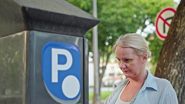 Woman using parking meter on city street