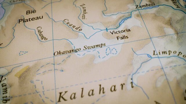 Gliding macro view over physical atlas map leading to the Kalahari Desert
