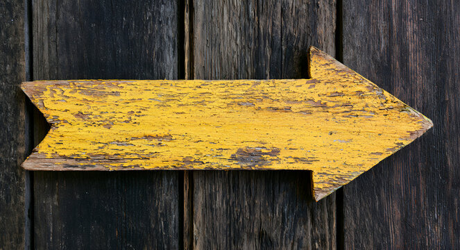 Rustic wooden sign with an arrow pointing right, painted yellow and weathered