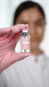 Pdrn polynucleotide serum vial in a gloved hand, salmon dna skin booster therapy, glass skin facial rejuvenation, regenerative aesthetics, collagen renewal, injectable anti-aging treatment