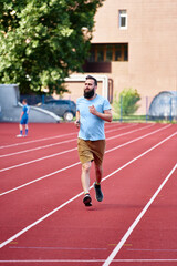 Obraz premium A man in casual clothing jogging on a red tar track outdoors during a sunny day, capturing concepts of exercise, fitness, and leisure in an urban environment.