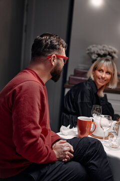 Two individuals enjoy a relaxed discussion, sitting across a table with beverages present, fostering connection and warmth.
