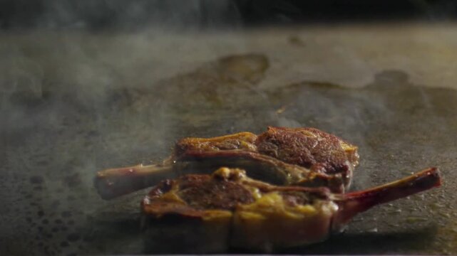 Lamb chops and potato cake cooking on a hot grill