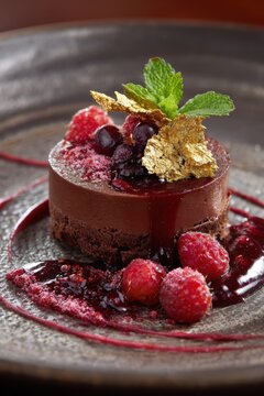 Fine dining dessert plated with precision featuring rich chocolate mousse raspberry coulis sauce and edible gold leaf garnish. Luxury indulgence artistic patisserie gourmet culinary excellence.