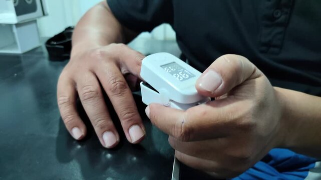 Doctor measuring blood oxygen saturation with pulse oximeter. Close-up of a medical professional attaching a fingertip pulse oximeter to a patient's hand to monitor vital signs, checking oxygen level