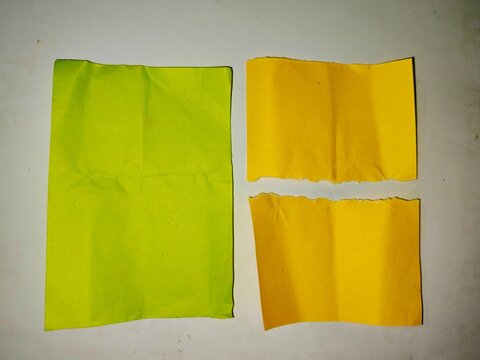 Crumpled green paper sheet and torn yellow note pieces, textured colorful paper scraps on white background
