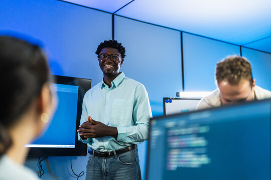 African male developer presents technical solutions and coding insights to team, demonstrating confident leadership and expert knowledge dissemination.