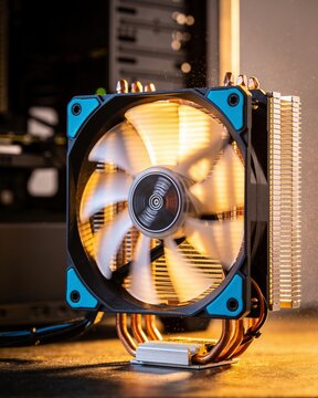 A glowing spinning cooling fan inside a computer case in a dimly lit dark data center room