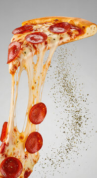 A delicious slice of pepperoni pizza with melting cheese stretching downwards on a grey background.