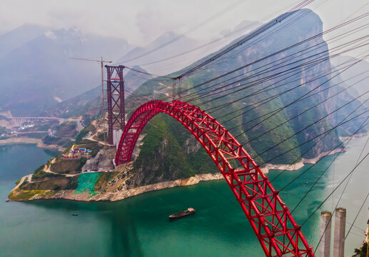 Red Arch Bridge Across Turquoise River in Mountain Valley
