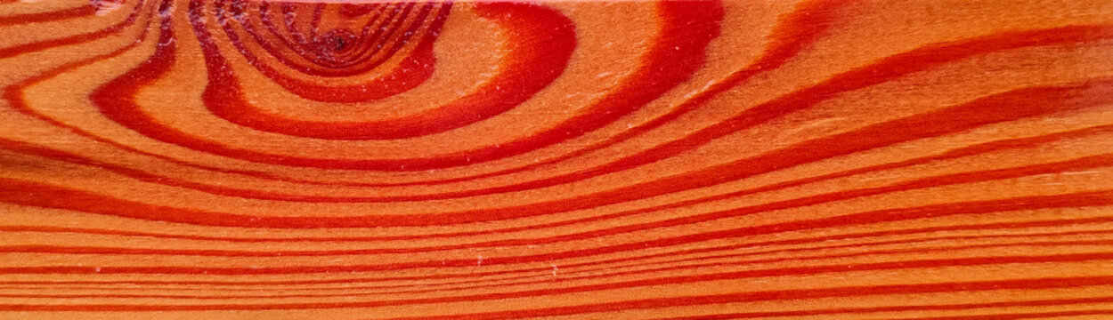 Vibrant orange red wood grain texture background with detailed swirling knot pattern