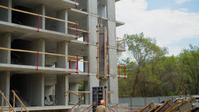 Concrete formwork panel lifted beside unfinished apartment building