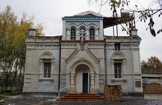 The historic Russian Orthodox Church of Saint Michael the Archangel features blue-trimmed white stone architecture under an overcast sky in Osh, Kyrgyzstan