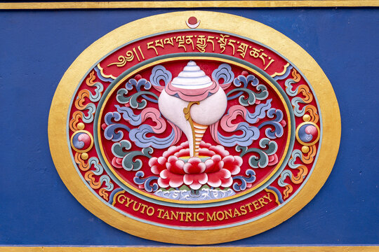 An ornamental emblem from the Gyuto Tantric Monastery in Sidhbari, Himachal Pradesh, India. It depicts a conch shell on a lotus flower, surrounded by cloud motifs.