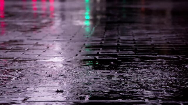 Summer Downpour in the City. Drops of rain fall on the paving slab. On a wet surface, the lights of the city are reflected