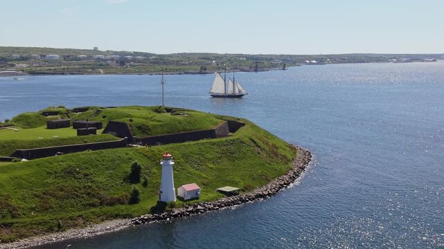 A majestic Bluenose gracefully sails through the serene waters of Halifax Bay, framed by breathtaking coastal scenery all around