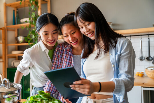 Happy beautiful chinese women friends bonding at home