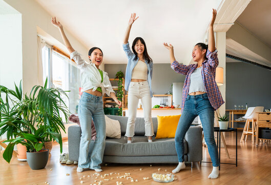 Happy beautiful chinese women friends bonding at home