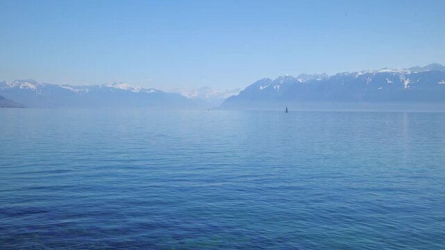 Wide angle shot of Lake Geneva with sailboats and majestic Alps mountain background