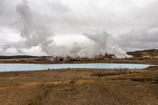 Blue silicated geothermal water lake with steam rising from a power plant in the background at Bjarnarflag near Myvatn Northeast Region Iceland