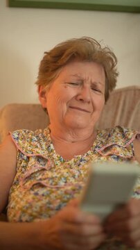 A retired senior woman at home playing a portable video retro game console and having fun