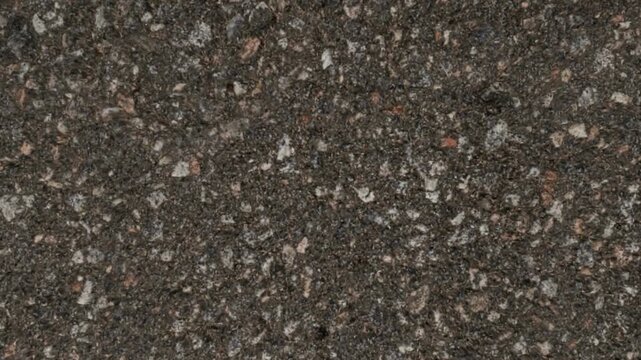 Detailed macro view of a dark rough asphalt road surface texture with embedded gravel, representing urban infrastructure.