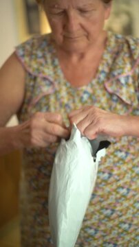 A senior woman is opening the shipment package at home closeup