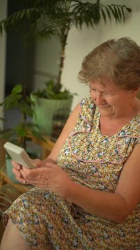 A retired senior woman at home playing a portable video retro game console and having fun