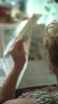 Senior woman reading a newspaper from behind closeup