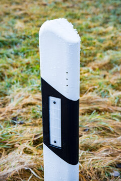 Frost covered delineator post standing beside a grassy field