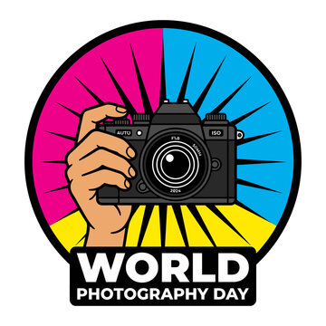 World Photography Day pop art badge featuring hand holding camera with colorful sunburst background and bold typography