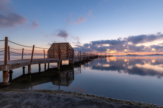 Colorful sunrise with the spa wooden walkway in the town of Los Urrutias, Cartagena, Mar Menor, Region of Murcia, Spain