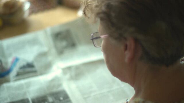 Senior woman reading a newspaper from behind closeup