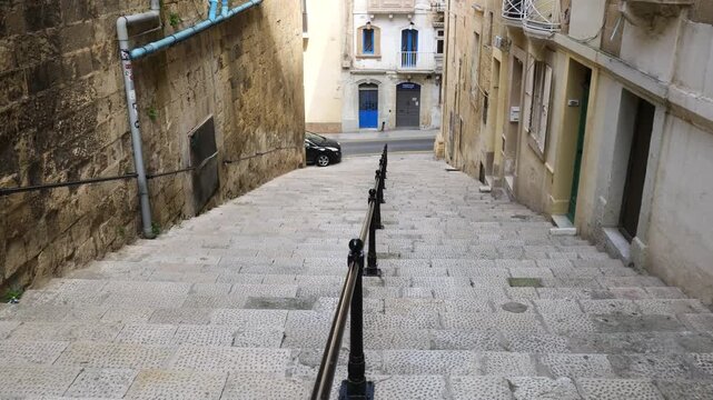 cobbled stepped ramp winds through valletta cars parked along the historic old town stairway street valletta side street stepped street cobbled street narrow malta street old town street