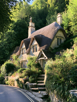 Historically, the thatched cottage perched amidst the verdant village of Castle Combe, Wiltshire, England, offers a picturesque setting.