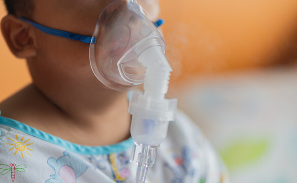 Allergy sufferers Oxygen sick children Sick boy inhalation therapy by the mask of inhaler. Worried sick kid with oxygen mask sitting on bed at hospital ward - concept of breathing problems